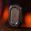 A close-up of a dark brown metal mechanical fidget slider with a gem design resting on a wooden surface.