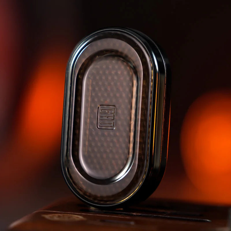 A close-up of a dark brown metal mechanical fidget slider with a gem design resting on a wooden surface.