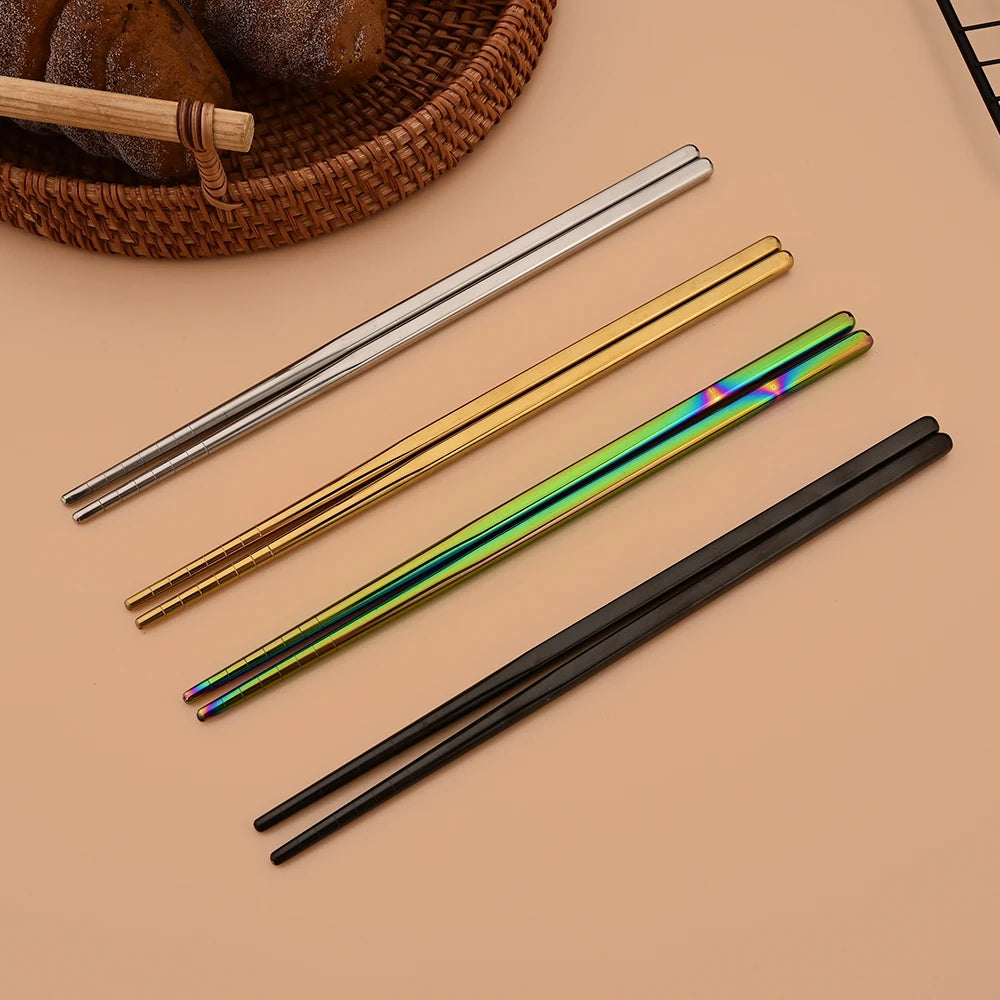 A set of six stainless steel chopsticks and dinnerware resting on a neutral background.