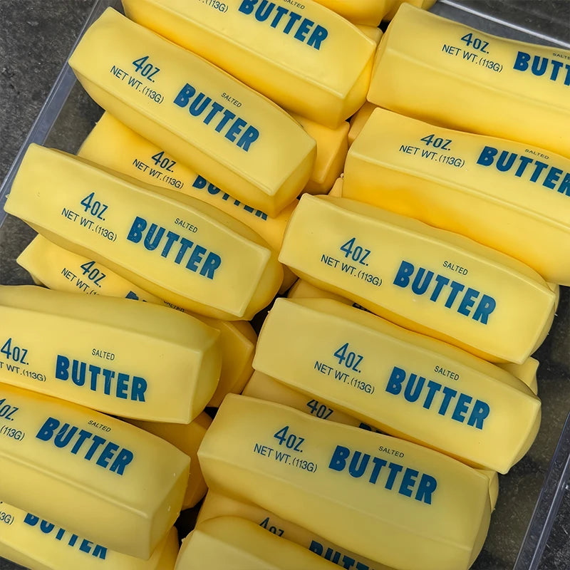 A pile of yellow butter stick squishy fidget toys with the word BUTTER printed on them.