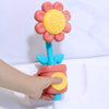 A hand is holding a pink and yellow sunflower bath shower sprinkler toy for kids