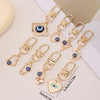 A set of gold-toned evil eye keychains featuring blue eyes and various shapes for bags and backpacks.