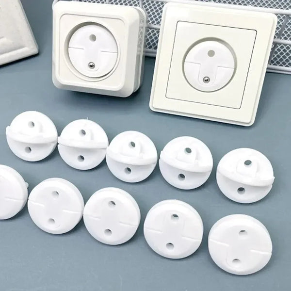 A collection of white childproof European socket safety plugs and a wall plate are shown on a gray surface.