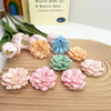 A collection of pink, peach, and blue silicone 3D carnation flowers used for candle making and crafting.