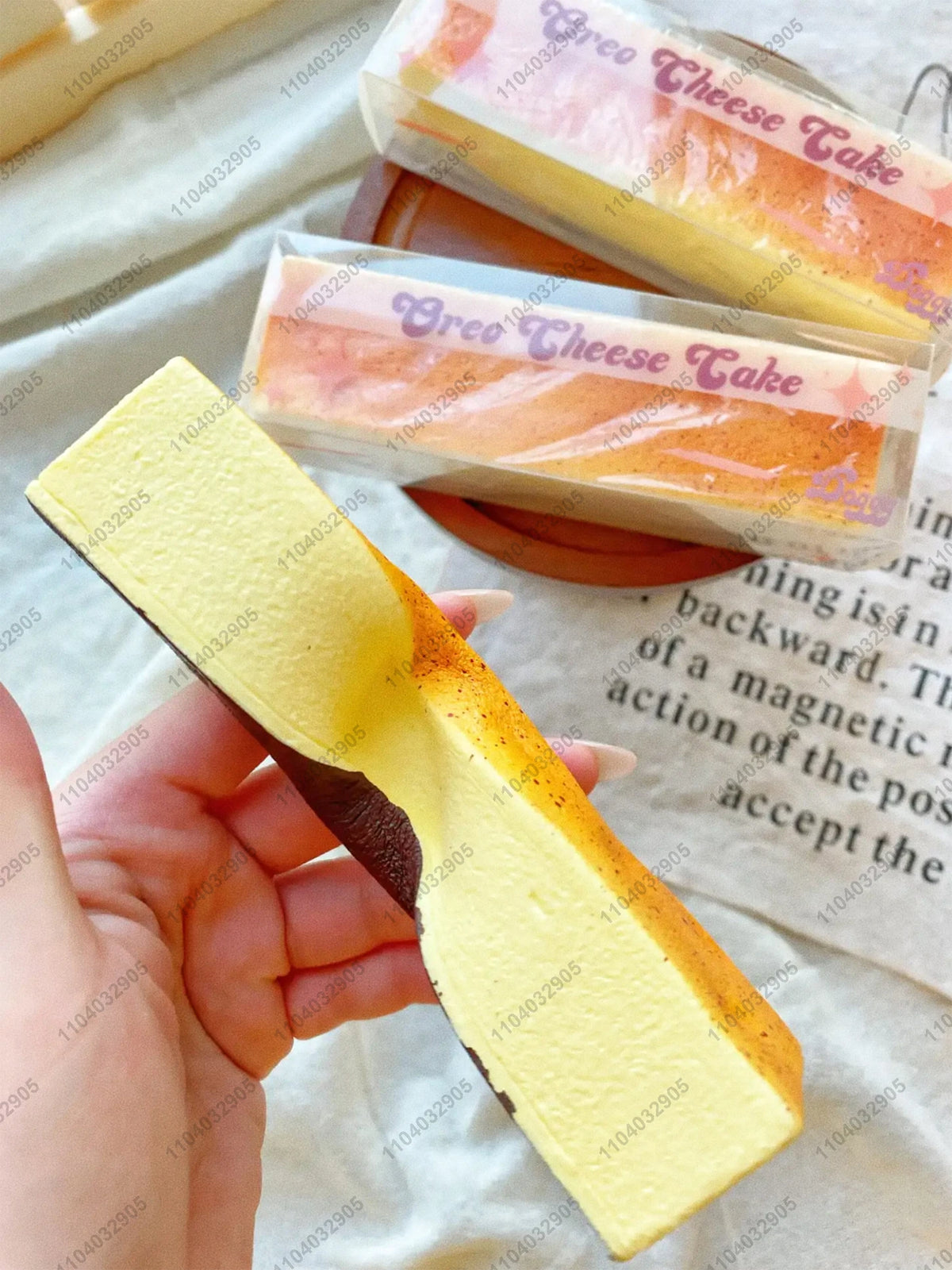 A yellow butter stick squishy toy is held in a hand next to packaged cheese take products.