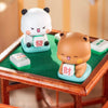 Un par de adorables figuras coleccionables de panda, una blanca y una marrón, sentadas sobre una superficie verde.