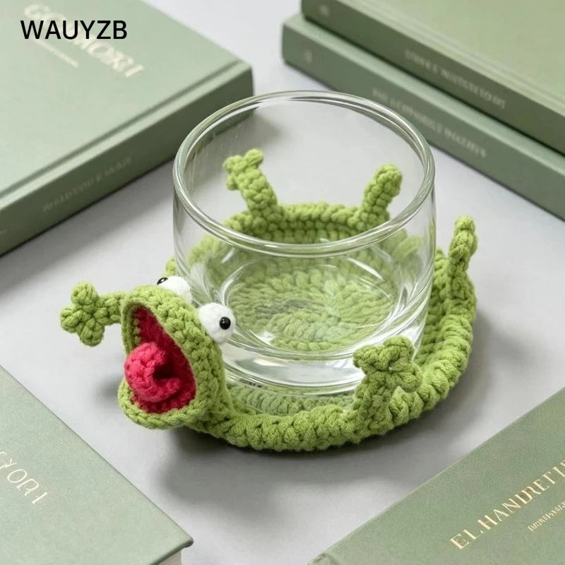 Handwoven crochet lizard coaster in green fabric resting on a light green book.
