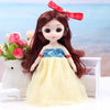 A 17cm articulated princess doll with long dark hair and a yellow tulle dress and red bow, set against a blurred blue sea bac