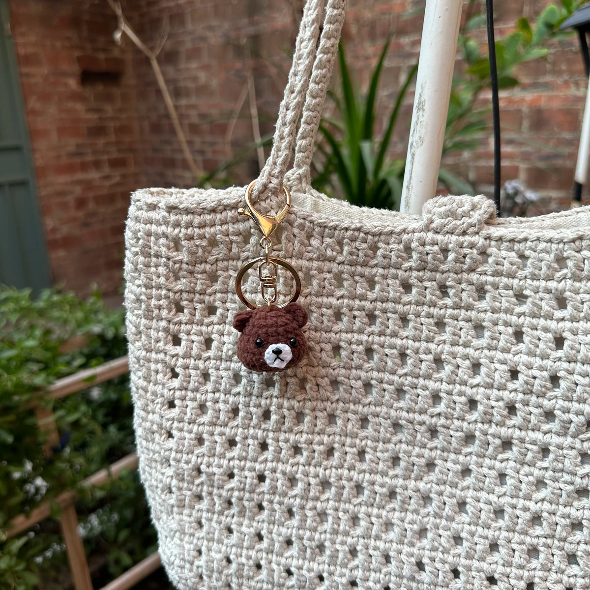 A handcrafted crochet animal keychain featuring a small brown rabbit charm attached to a beige woven bag.