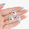 Gold enamel marine life charms shaped like dolphins and waves displayed on a hand