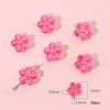 A collection of pink acrylic flower beads, some on a silver hook, displayed on a light pink background.
