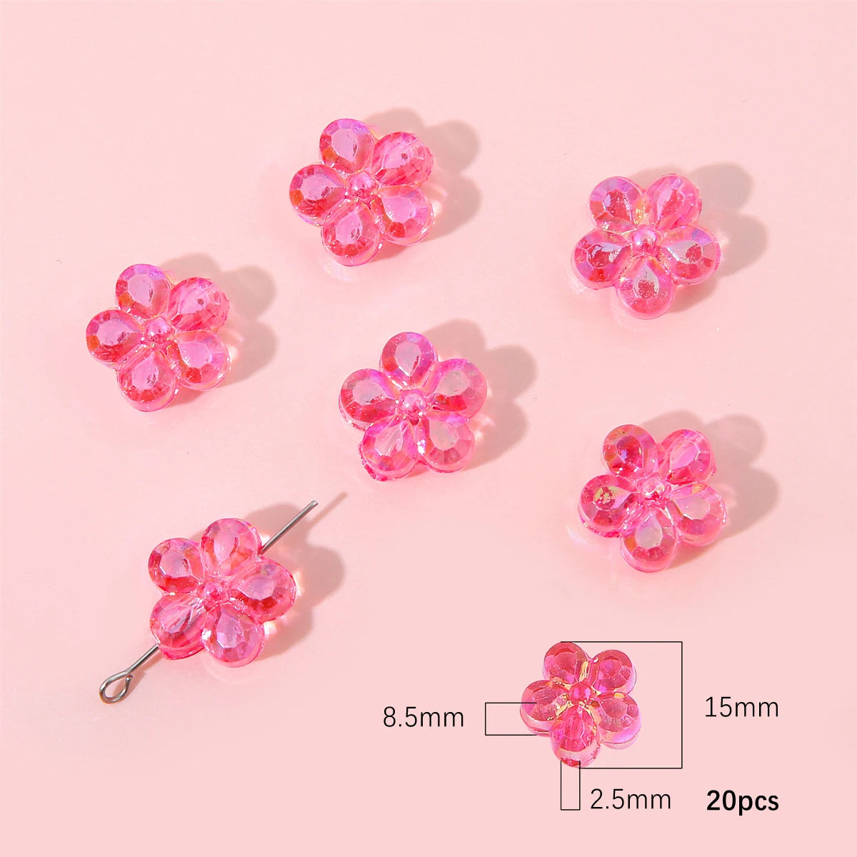 A collection of pink acrylic flower beads, some on a silver hook, displayed on a light pink background.