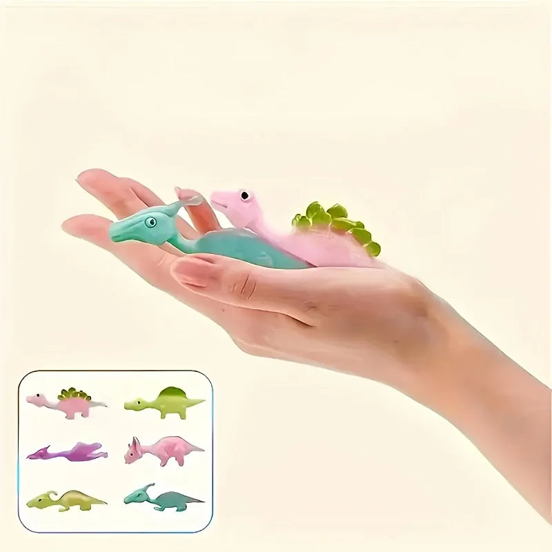 A hand holds several colorful mini dinosaur finger slingshots, including pink, green, and purple varieties.
