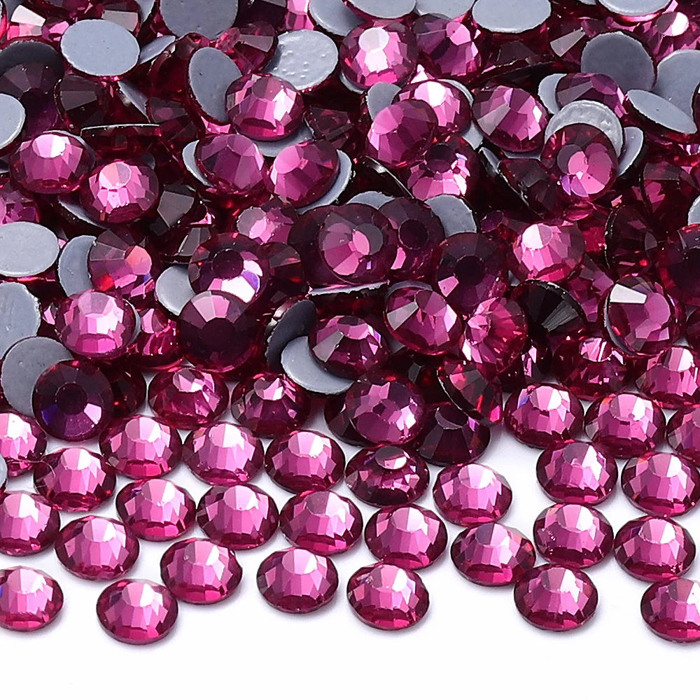 A close-up view of small, faceted glass crystal hot fix rhinestones in various shades of pink and magenta.