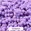 A close-up view of small, pastel purple bear-shaped acrylic craft beads scattered on a surface.