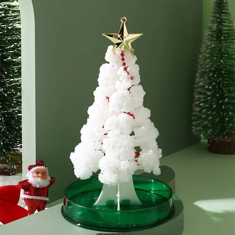 A white flocked Christmas tree decoration topped with a gold star, placed on a green circular base next to a Santa figurine.