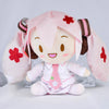 A pink Hatsune Miku plush doll with large ears and a white outfit, featuring red flower accents.