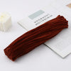 A bundle of dark reddish-brown chenille craft stems lying next to an open book titled Minimalism.