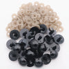 A collection of black plastic safety eyes with washers and light beige plastic eyes for crafting.