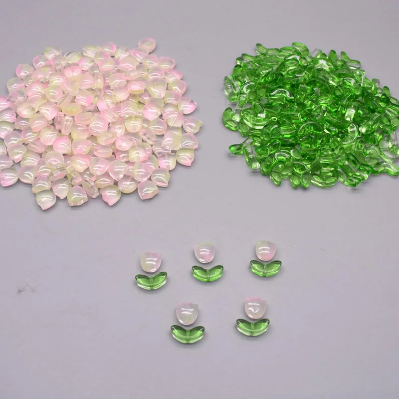 A collection of pink and green tulip flower glass beads, including loose beads and small packaged sets.