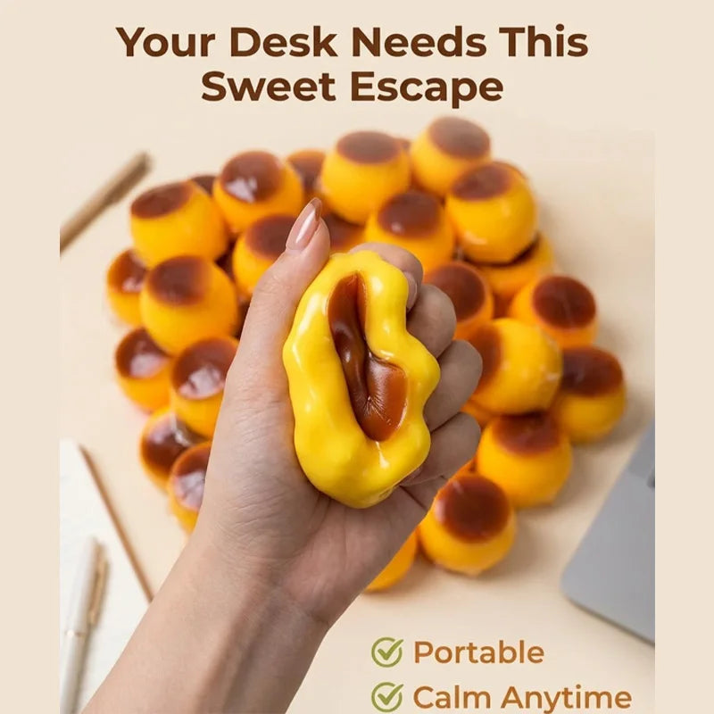 A hand holds a yellow caramel pudding squishy stress relief ball on a light background.