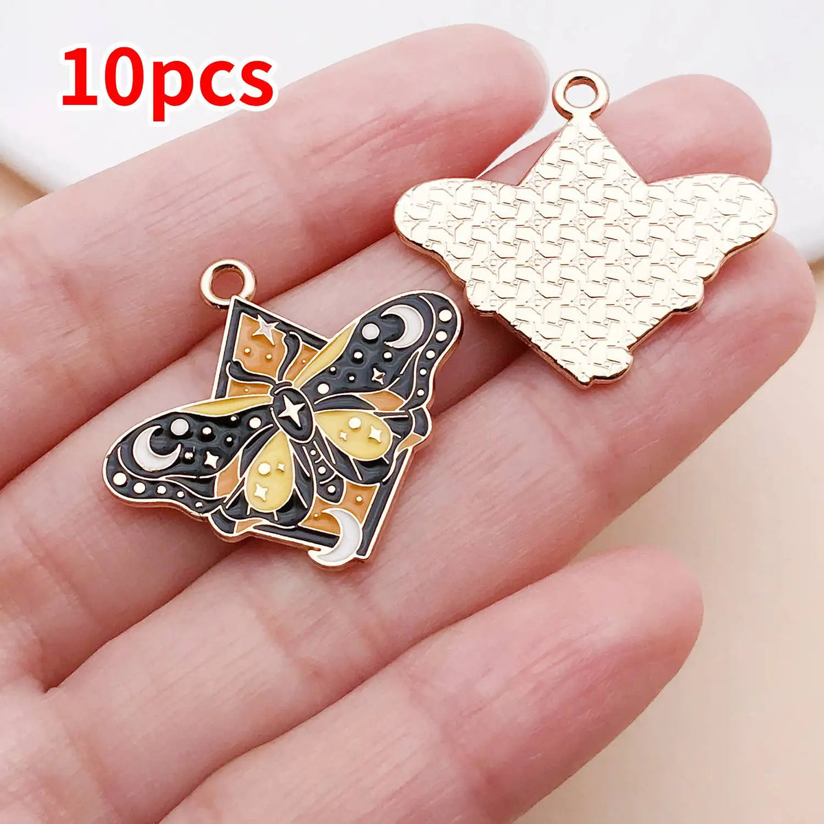 Ten gold-toned butterfly drop charms are displayed on a hand, showing their intricate detail.