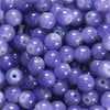 A close-up view of small, round glass beads in various shades of purple and blue.