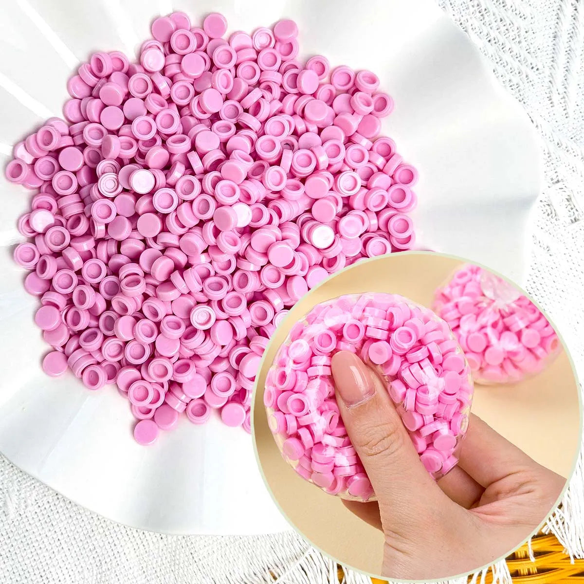 A pile of pink plastic beads is shown next to a hand holding a pink squishy toy.