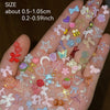 A close-up of a hand displaying a variety of multicolor resin nail charms and embellishments.
