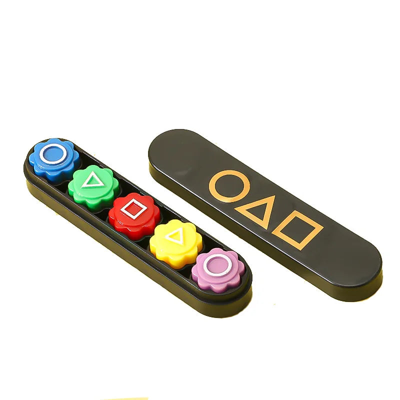 A set of five colored gonggi stones, including blue, green, red, yellow, and pink, displayed in a dark rectangular case.