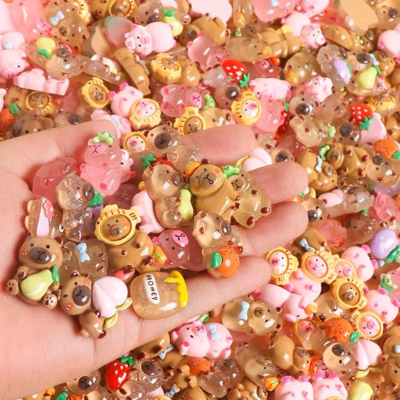A hand holds a pile of mini capybara resin figurines in various colors for desk decor and crafts.