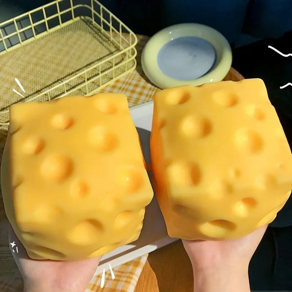 A pair of yellow giant squeeze cheese fidget toys are held against a light background.