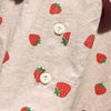 Pink long-sleeve shirt for a baby girl with a repeating red strawberry print.