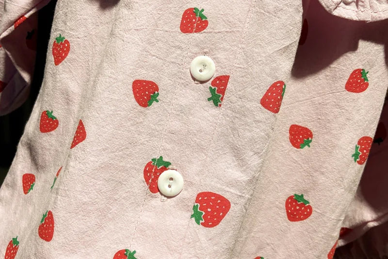 Pink long-sleeve shirt for a baby girl with a repeating red strawberry print.