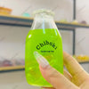 A hand holds a clear bottle filled with bright green liquid, labeled Chiboki drink cup toy.