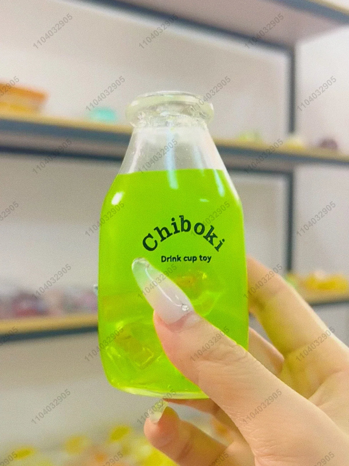 A hand holds a clear bottle filled with bright green liquid, labeled Chiboki drink cup toy.