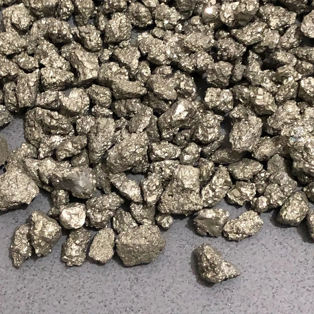 A pile of metallic gold natural crystal chips consisting of chalcopyrite and pyrite minerals.