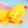 A bright yellow squishy duck fidget toy is shown lying on a light blue surface.