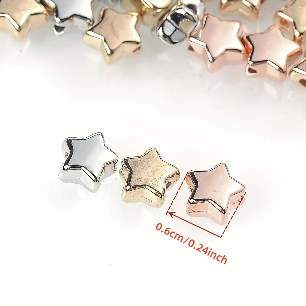 A close-up of gold and silver acrylic star and heart spacer beads for jewelry making.