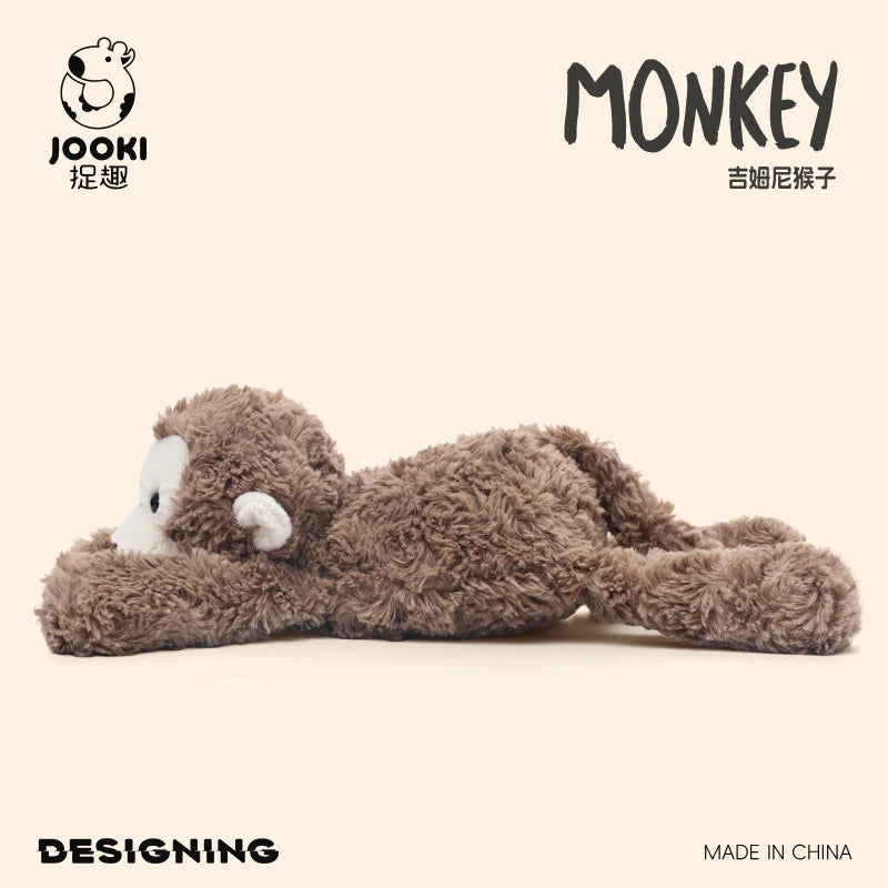 A fluffy brown monkey plush toy is shown lying down on a light background.