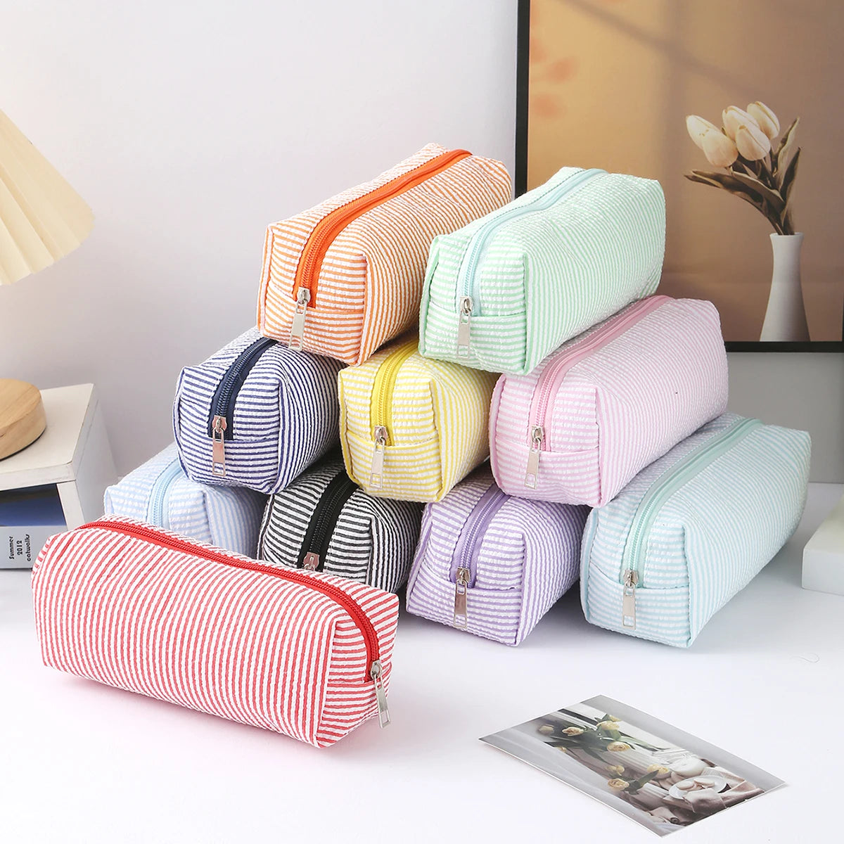 A collection of colorful striped canvas pencil cases in various pastel shades and patterns displayed on a white surface.
