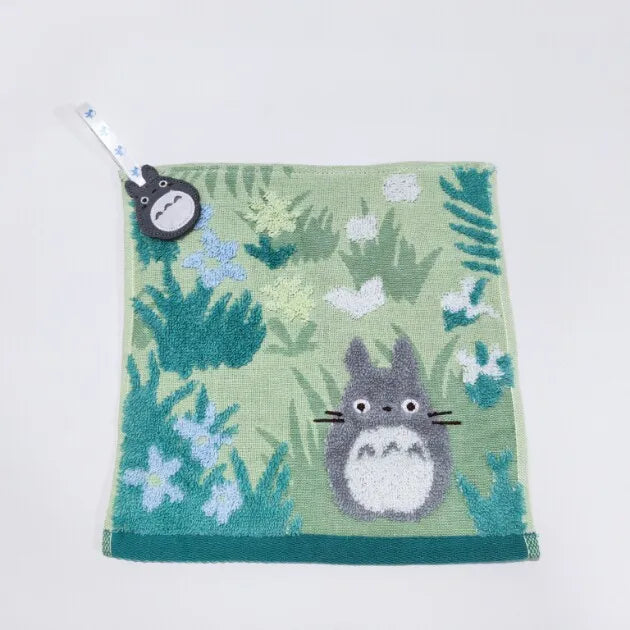 A soft green plush toy of a cat with gray fur and white accents, featuring a small tag.