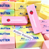 A collection of pink and yellow squishy butter stick fidget toys with strawberry and butter flavors.