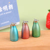 Three miniature alloy kettles in teal, copper, and olive green sitting on a wooden surface.