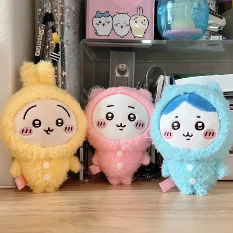 Three plush keychains in yellow, pink, and blue with a sleepy face design.