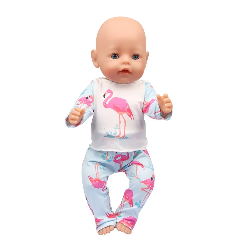 A baby doll wearing a light blue unicorn pajama set featuring pink flamingos