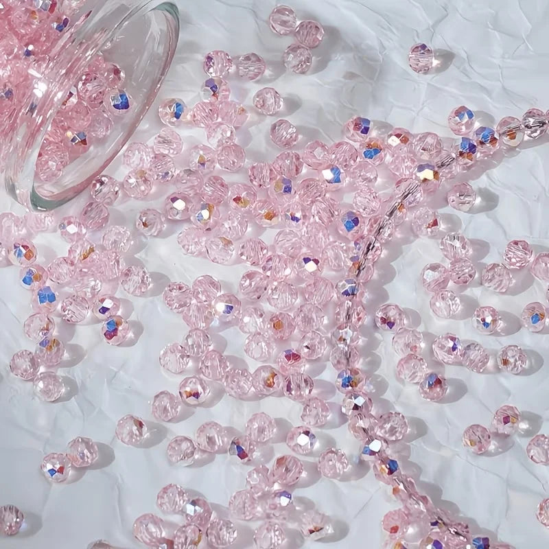 Pink and iridescent aurora cut glass beads scattered on white fabric