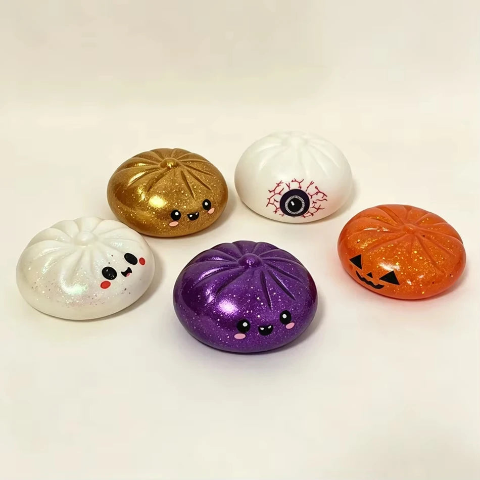 A set of three glitter stress relief balls shaped like a pumpkin, an eyeball, and a skull for Halloween