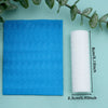 A roll of white clay texture rollers next to a blue patterned surface and green leaves.