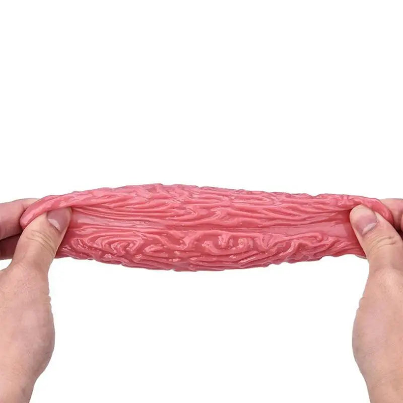 A hand is squeezing a pink, brain-shaped stress relief ball for anxiety and focus.